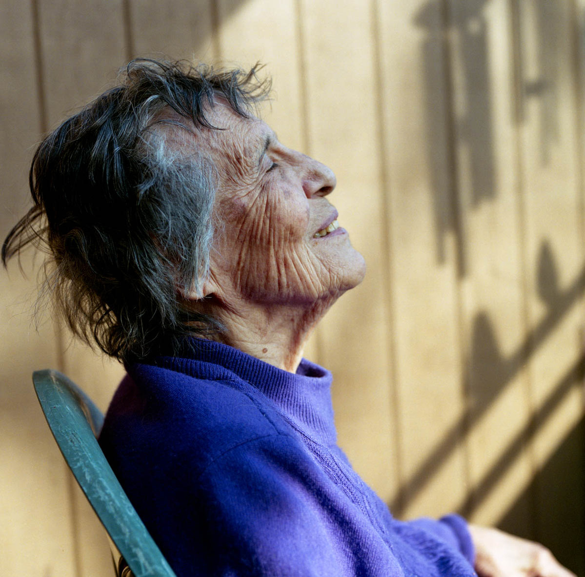 an elderly woman sitting in the sun on her front deck; part of a series on Medical Assistance in Dying
