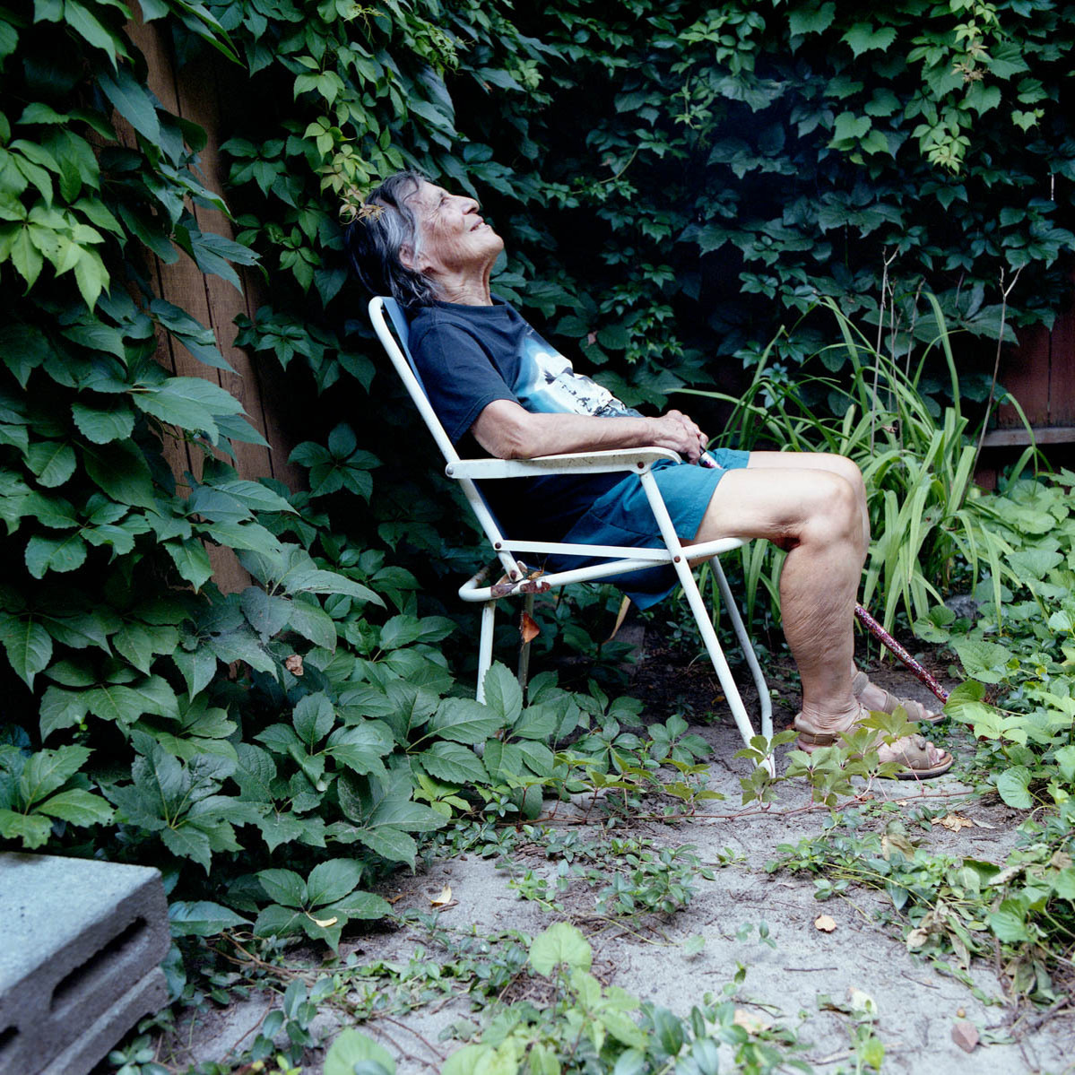 An elderly women sits in her back garden staring up at the sky; part of a photo series on Medical Assistance in Dying