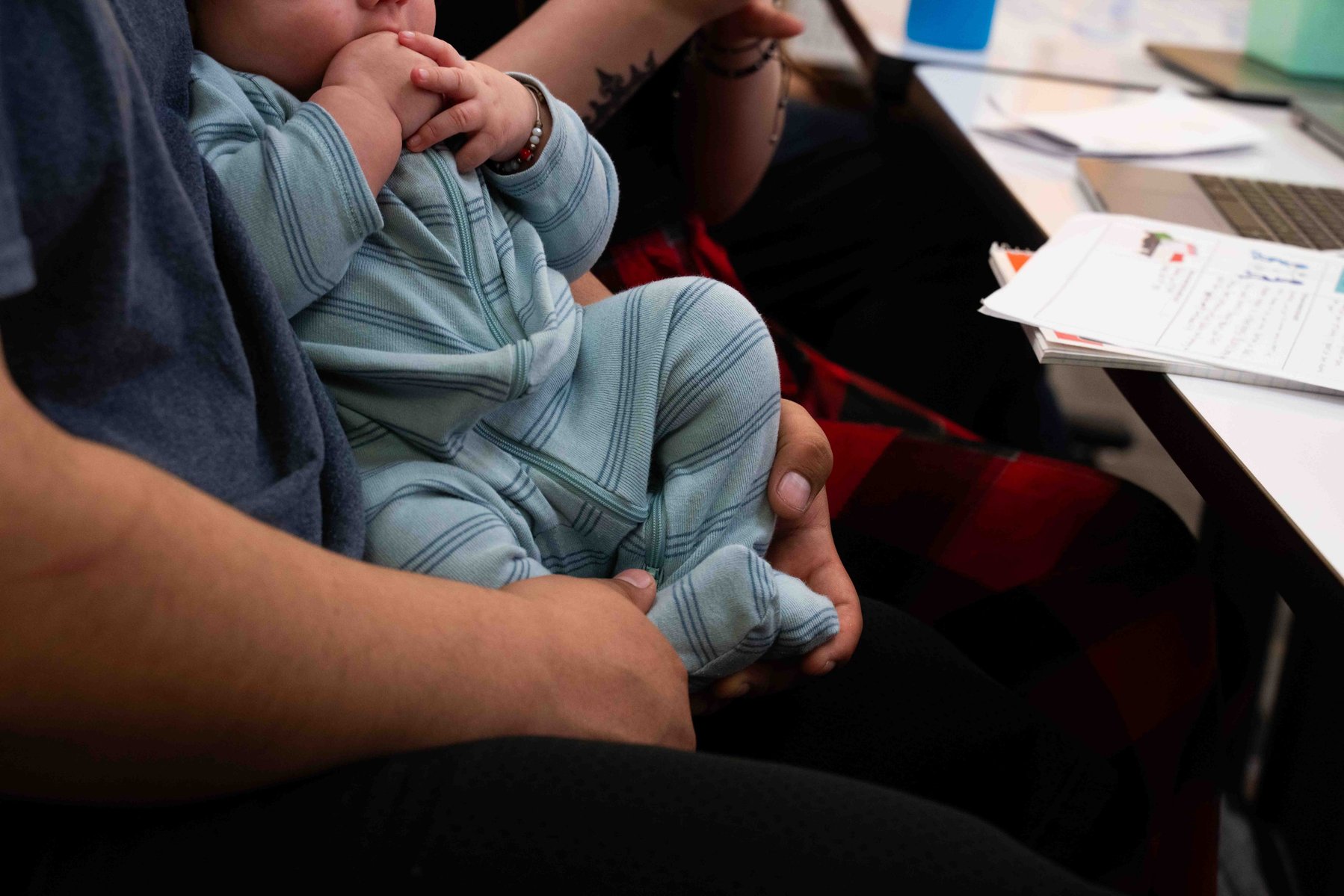 Rene, a senior at Lumen, holds his son RJ during class.