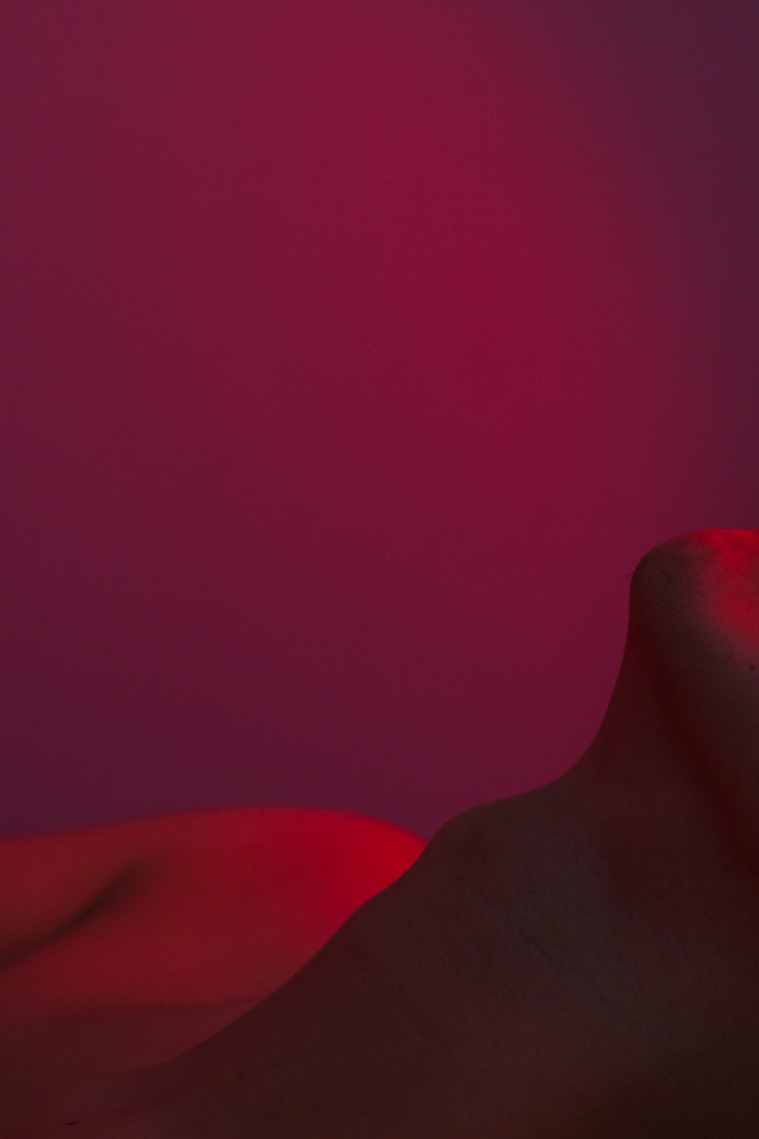 Neck area of a man in nude under the purple light which looks like a landscape of the desert area and very surreal because of the color