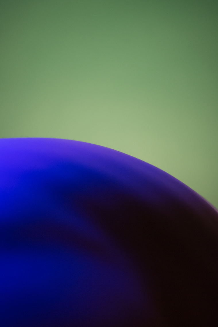 Back of man in nude and the curvature of the body resembles the landscape of nature. Body is in blue color and the background is in green color