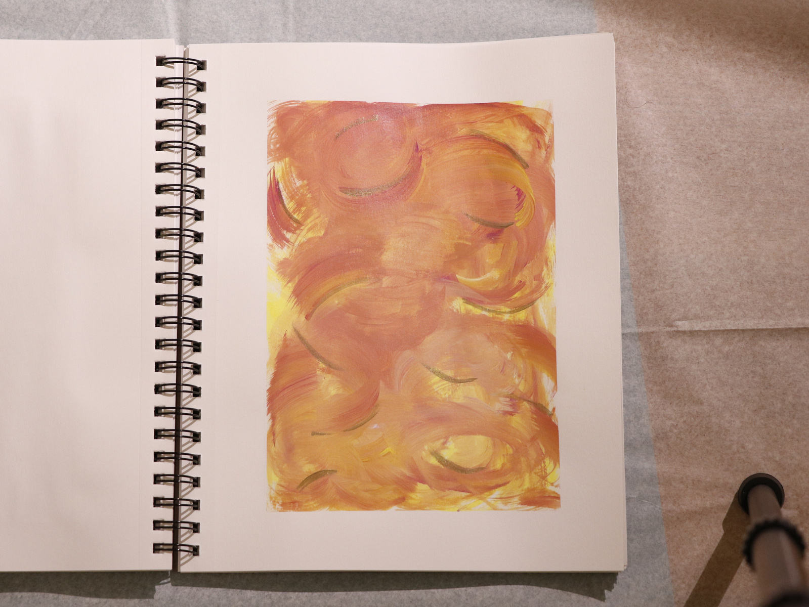 A tripod leg showing on the right side of the image with a painting in a sketchbook in the centre, ready to be taken a picture of.