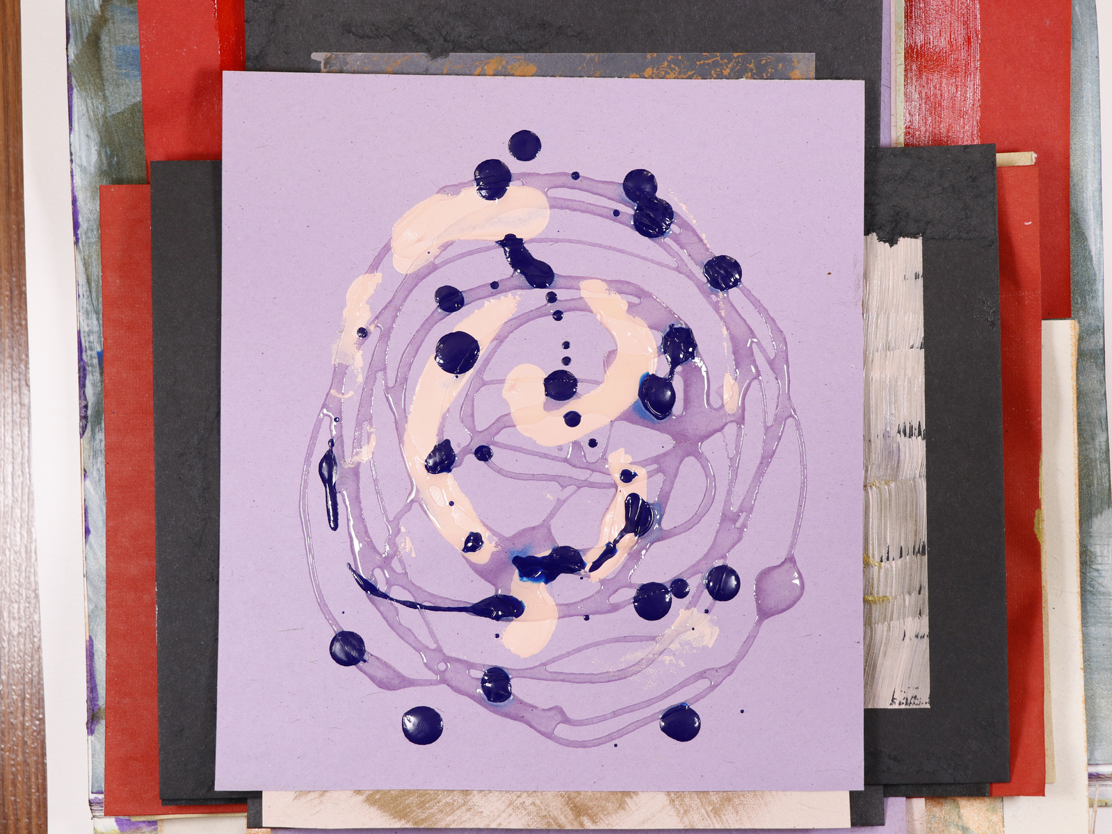 A stack of paintings with a purple painting on the top.