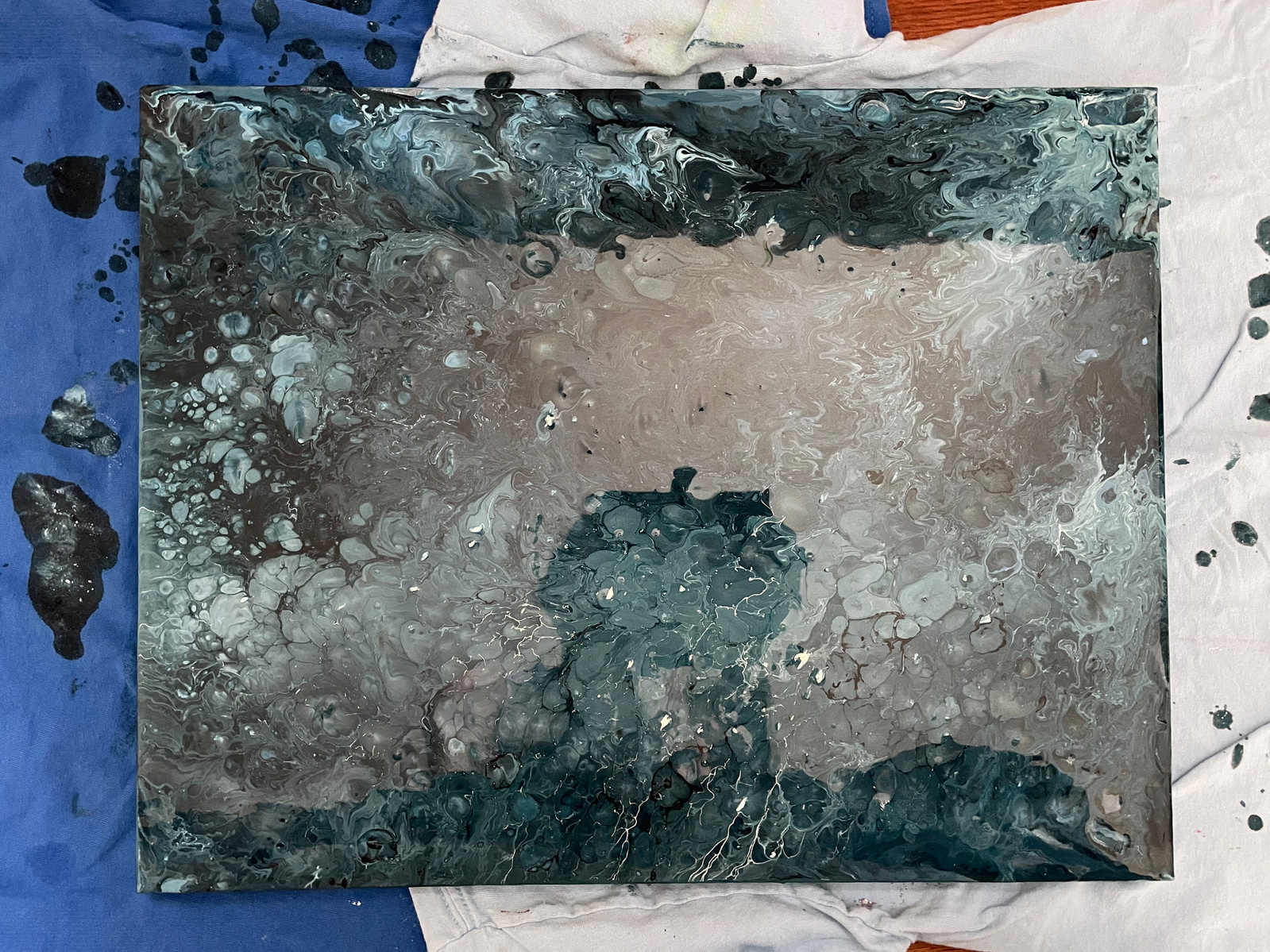 A freshly made acrylic pouring painting with the reflection of a mobile phone.