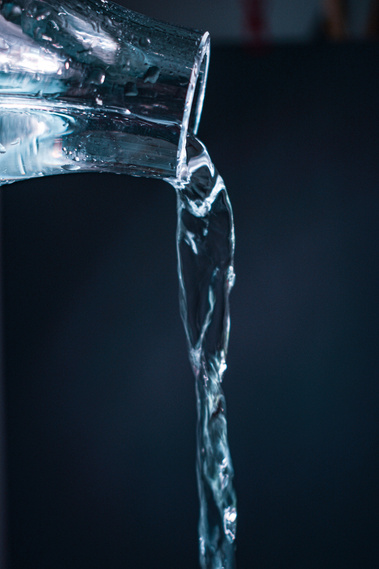 A stream of water flowing from a transparent glass container