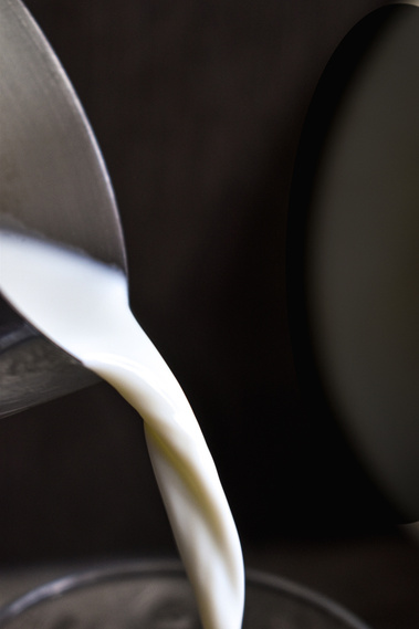 A stream of milk running from a metal pitcher