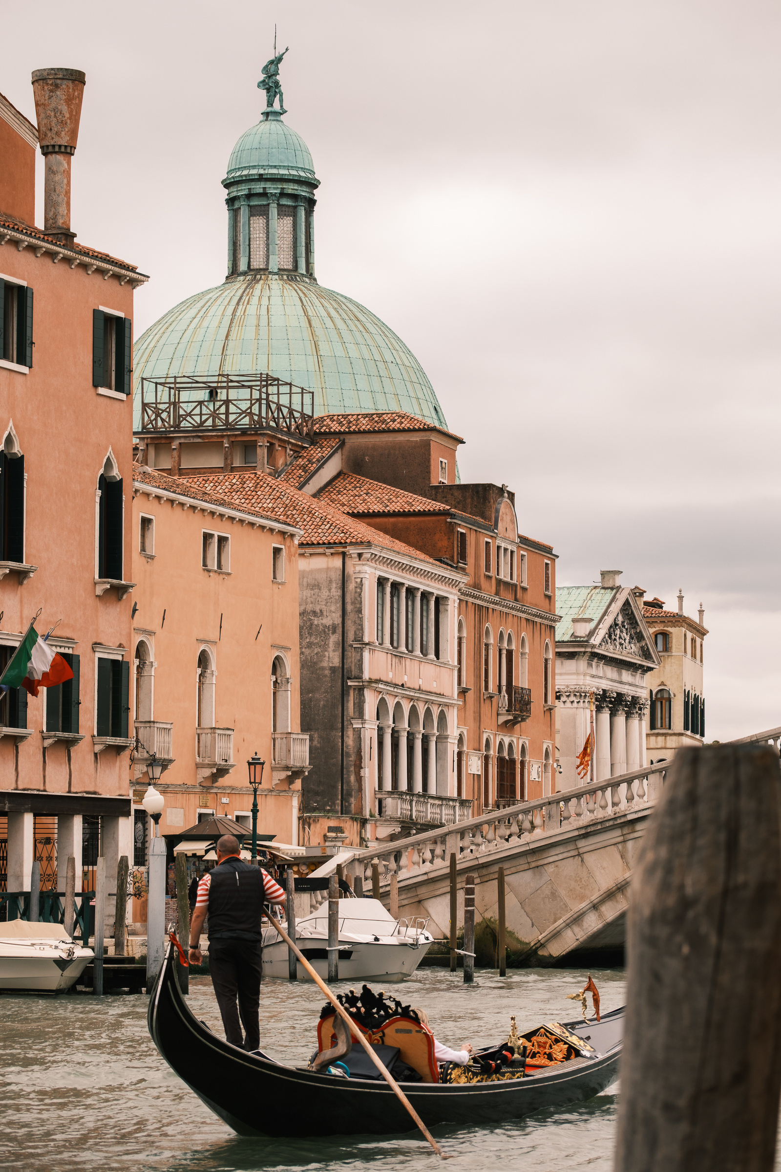 A gondolier passes through a Venetian canal, with the flag of Italy in the background, Venice Italy