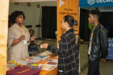 Exhibitor and attendee at a health-screening booth during a corporate expo