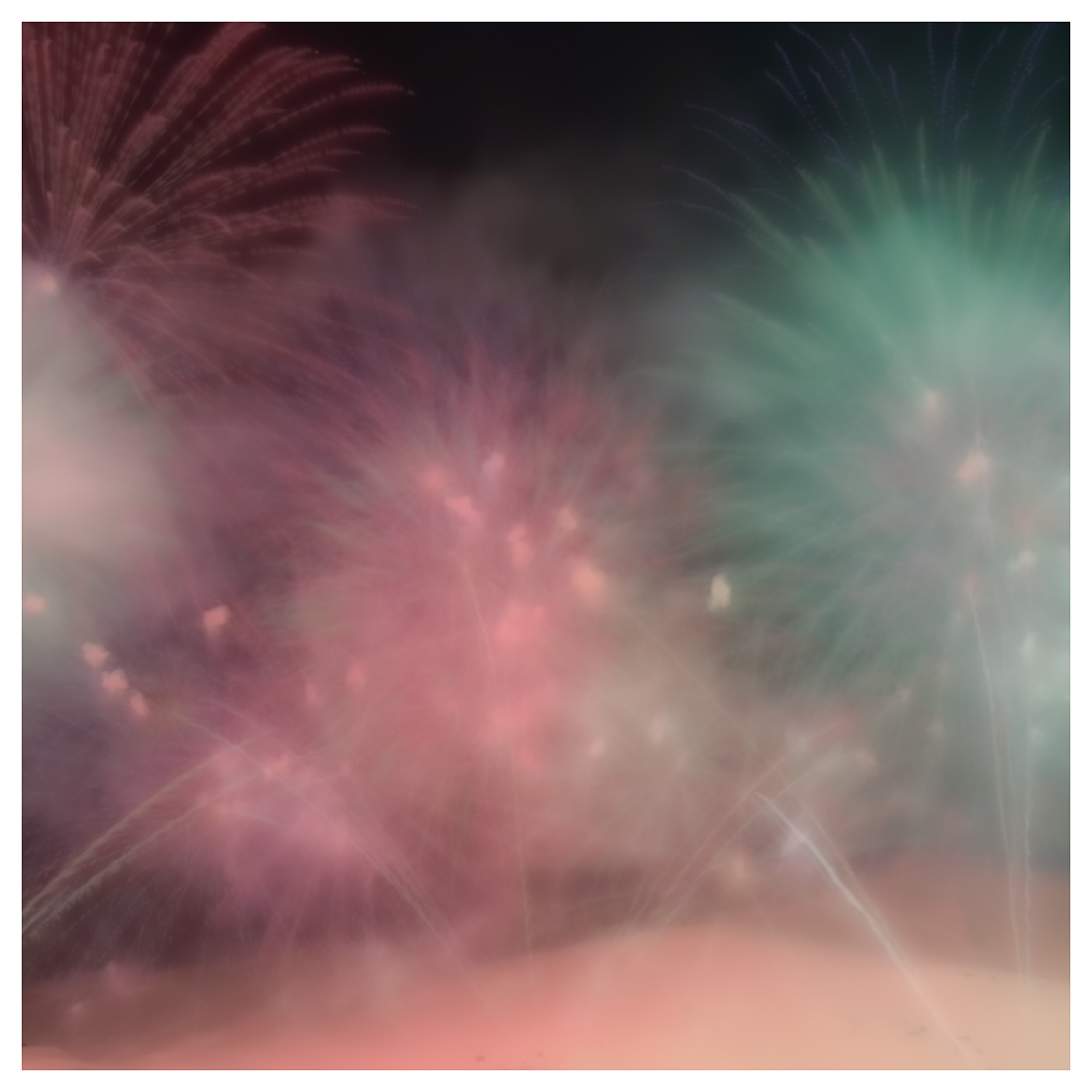 Fireworks explode over a snow covered mountain creating a pink and green dispaly
