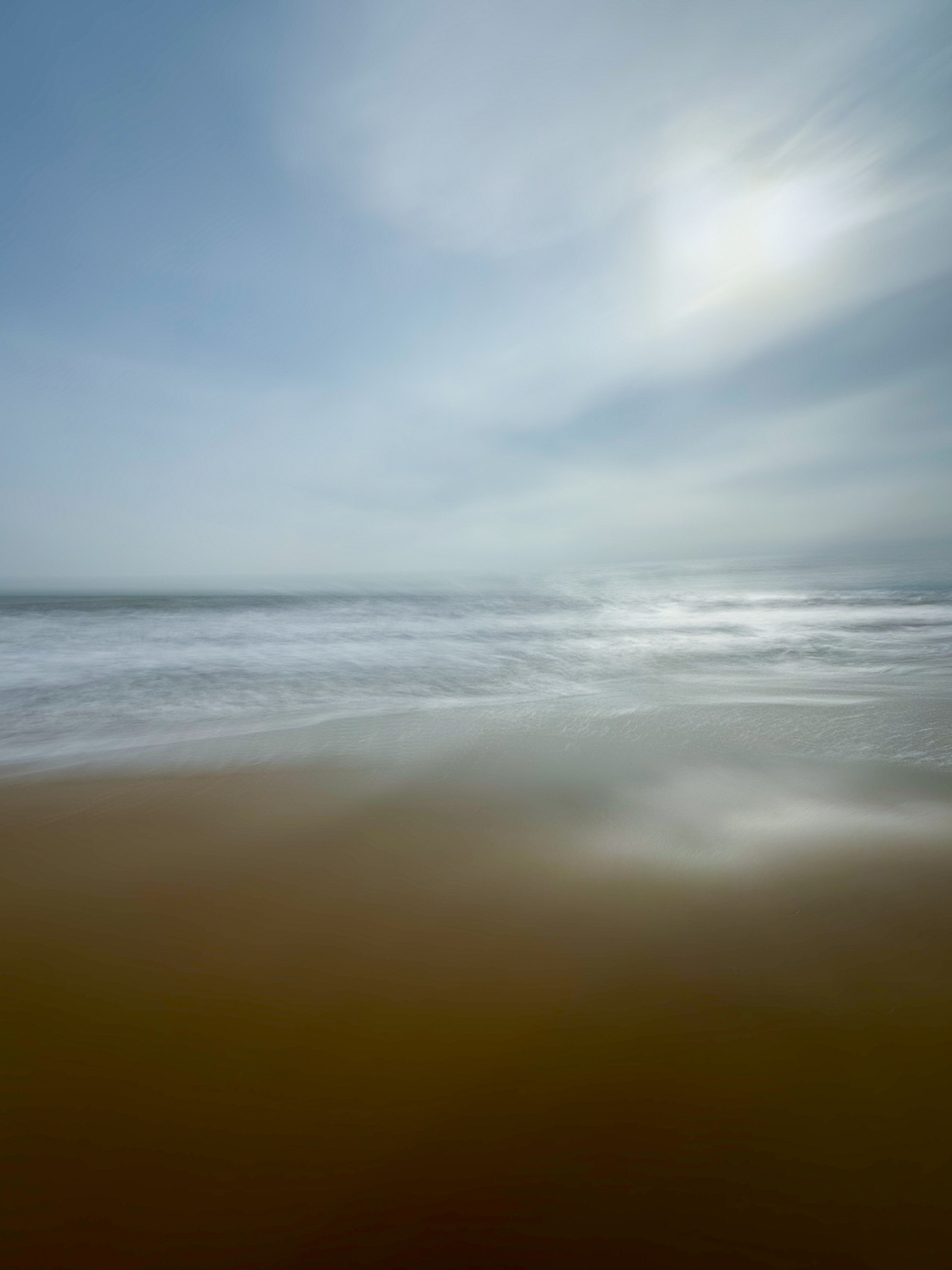 The light hits the sea and brightens it white, the sea and sky have been blurred
