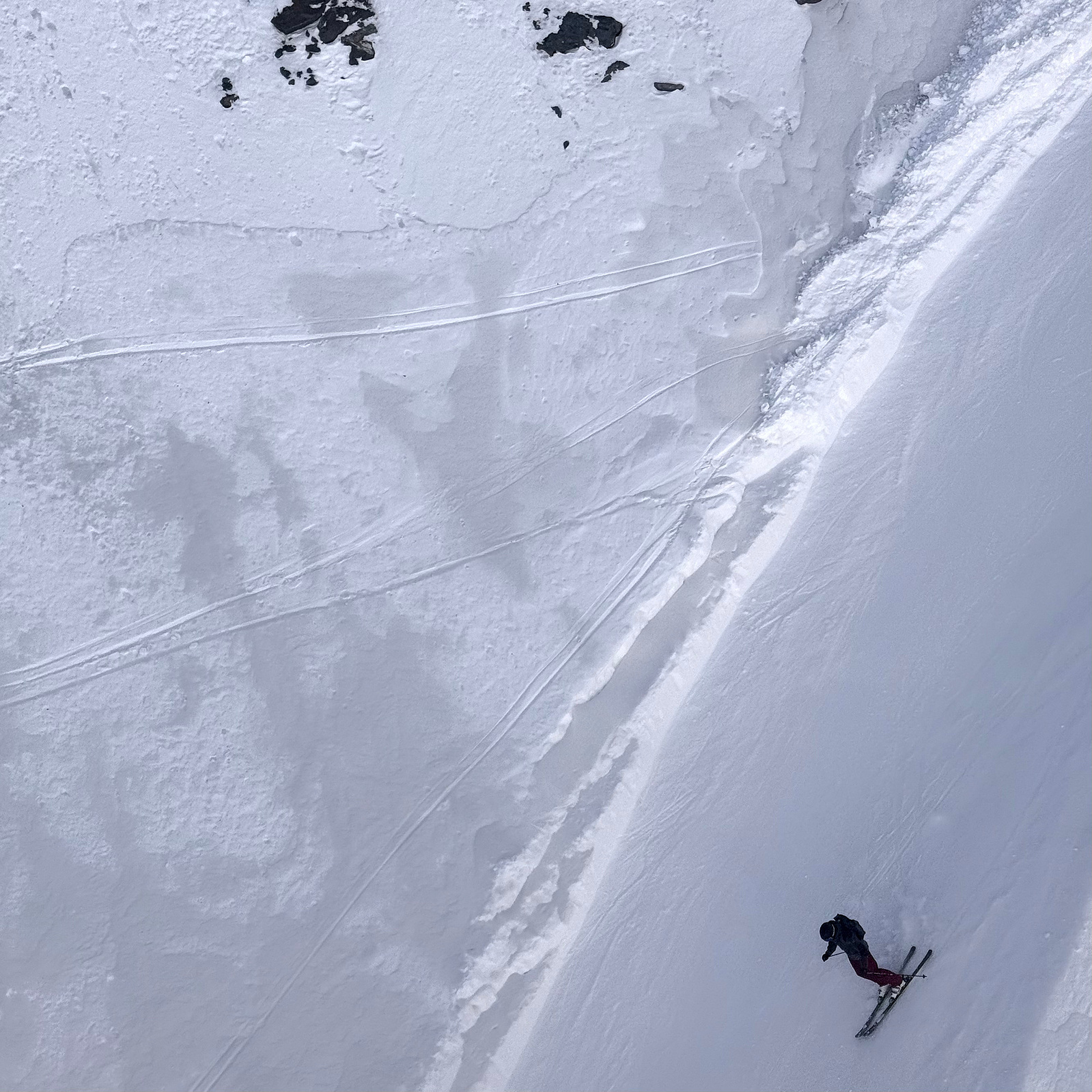 Taken from above, the skier appears miniscule compared to the scale of the mountains