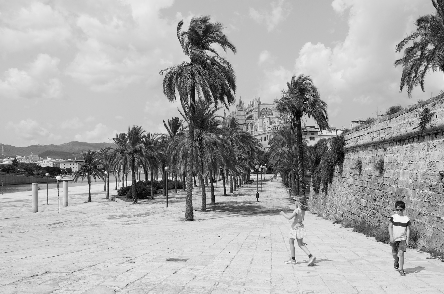 A young girl and her younger brother walk along a street in Palma, Mallorca
