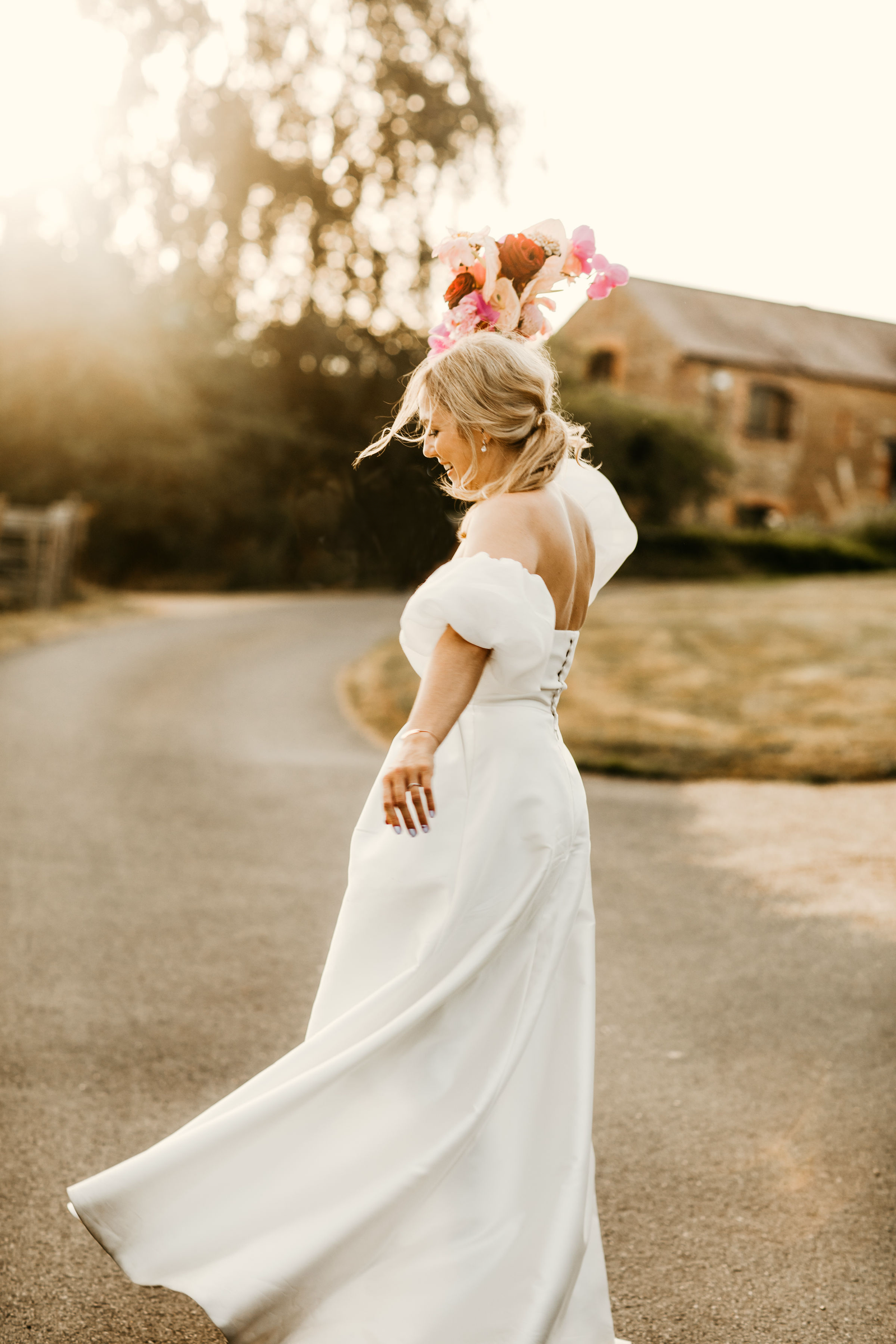 Bride dancing against a sunset backdrop holding her bouquet in the air 
