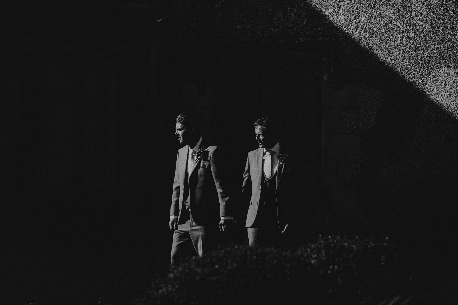 Black and white image of two men holding hands in the afternoon sun