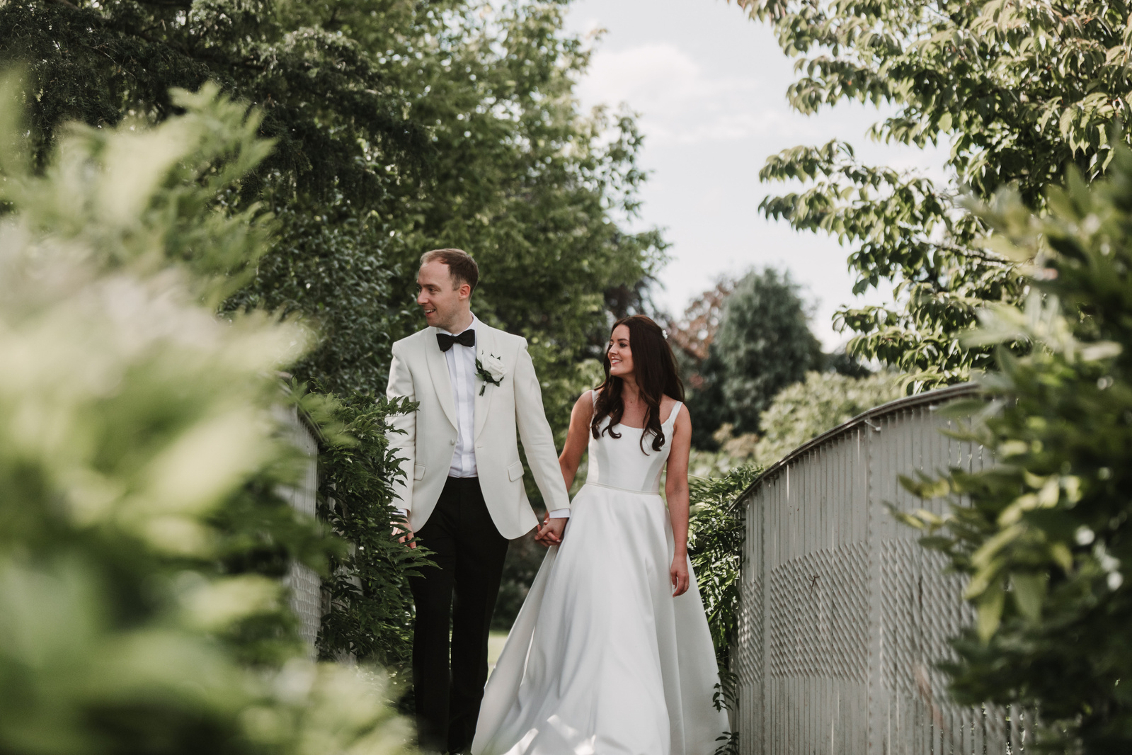 A couple crossing a bridge over a stream at a Cotswolds wedding venue 