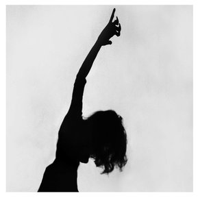 Black and white fine art photography self portrait by contemporary artist Di Allison, HALLISON Studios, Tasmania, from the series Muted Shadows. Distorted woman with long hair and outstretched raised arm and lowered head.