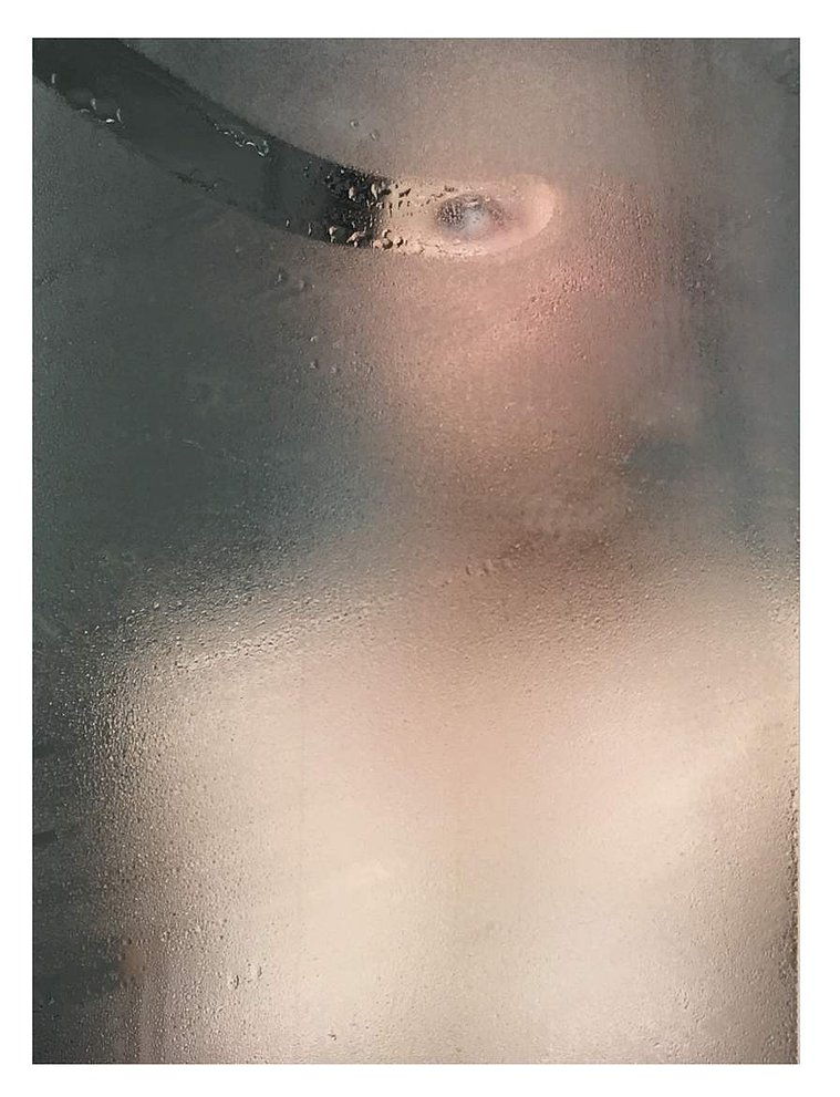 Fine art photography by Di Allison, HALLISON Studios, Tasmania, online gallery store. Self portrait in a mirror with condensation, water, drips on the glass, foggy. A streak on the glass reveals the woman's eye. Entitled The Looking Glass.