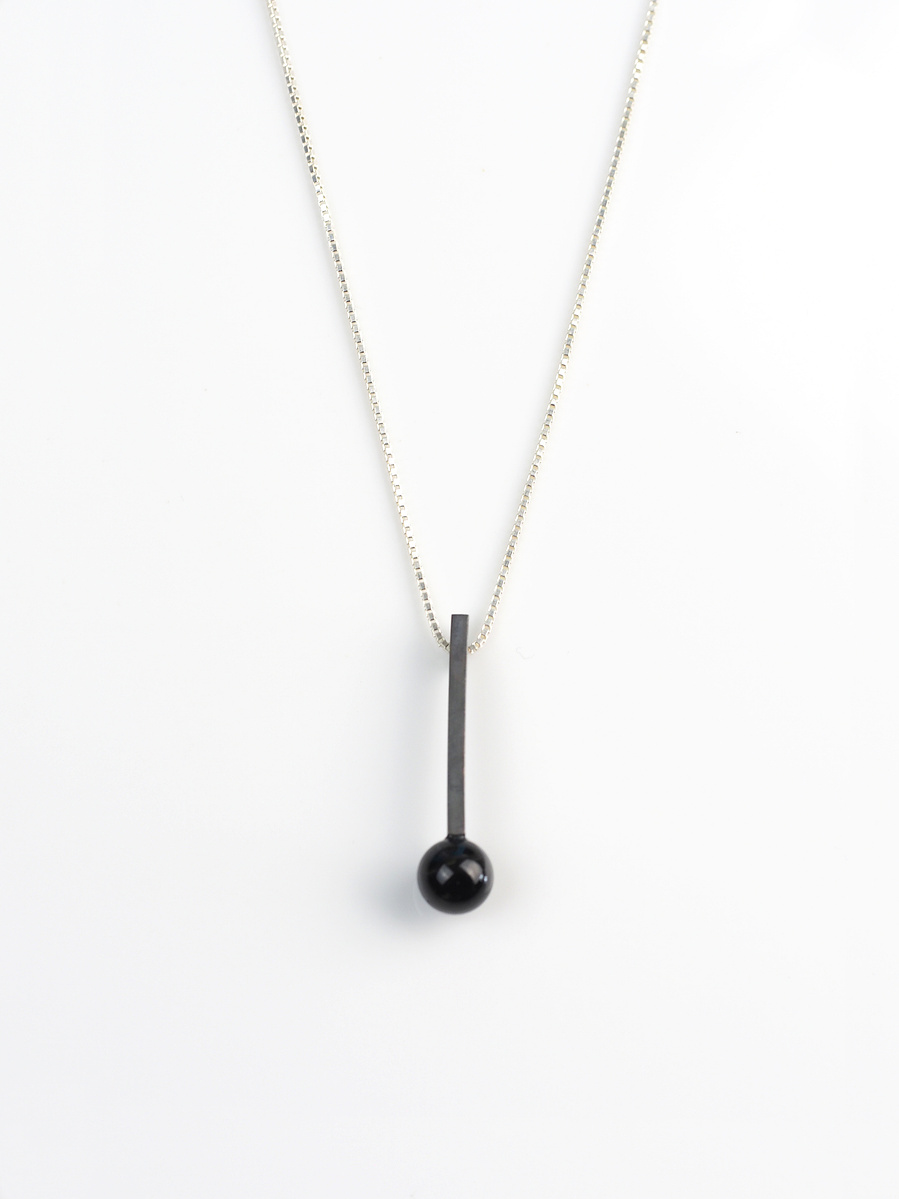 Oxidised sterling silver stem and black road agate pendant by contemporary jeweller Di Allison of HALLISON Studios, Tasmania, entitled Exclamation!. The pendant is shaped like an exclamation mark. 