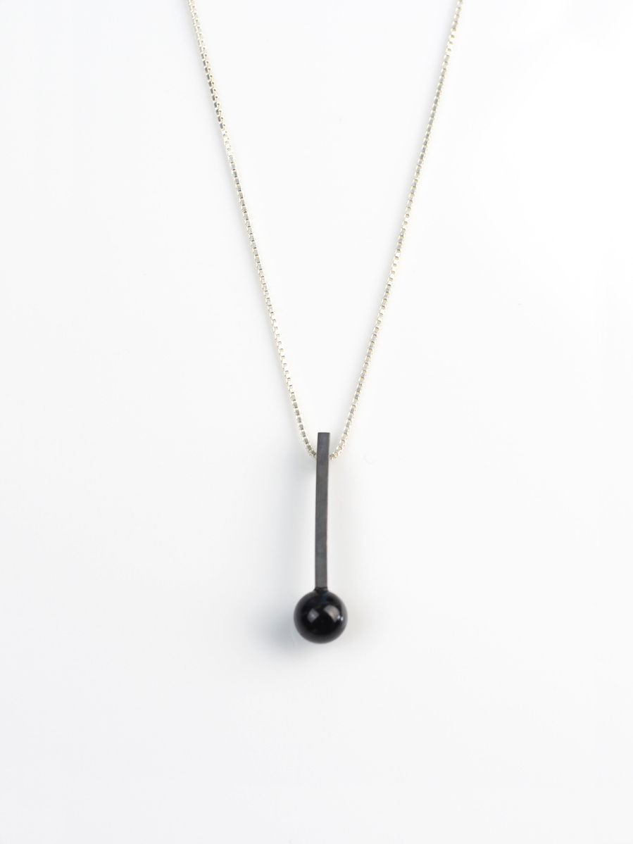 Oxidised sterling silver stem and black road agate pendant by contemporary jeweller Di Allison of HALLISON Studios, Tasmania, entitled Exclamation!. The pendant is shaped like an exclamation mark. 