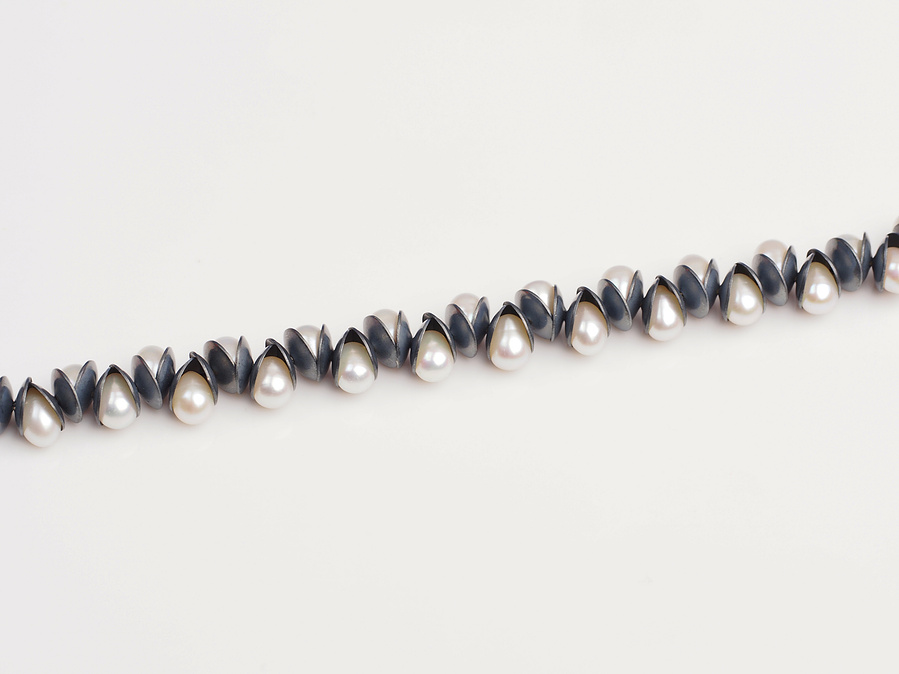 Nestle: Luminous bracelet on a white background is a strand of white freshwater pearls nestled between oxidised and domed sterling silver by  contemporary jeweller Di Allison of HALLISON Studios, Tasmania.