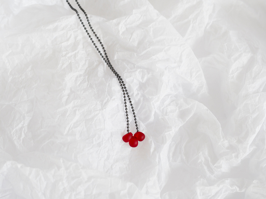 Sleeping Beauty pendant, contemporary jewellery by Diane Allison, HALLISON Studios, Tasmania. Oxidised sterling silver chain with three blood red droplets photographed on a white textured background like snow or ice.