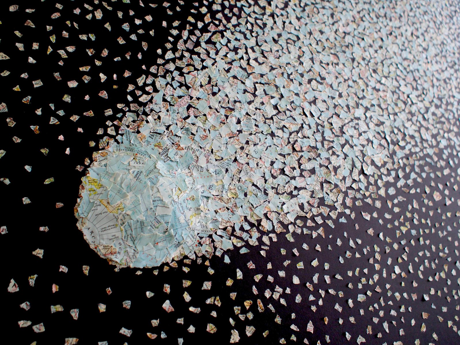 Close-up detail of Dust to Dust - a large collage by visual artist Di Allison, HALLISON Studios, Tasmania.  Contemporary art collage featuring a National Geographic magazine world map ripped into small pieces, arranged like a comet against a night sky. 