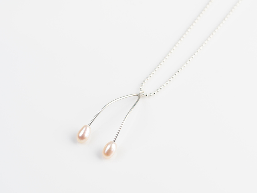 Sterling silver and white freshwater pearl pendant entitled Wish, against a white background. Made by contemporary jeweller Diane Allison, HALLISON Studios, Tasmania. This piece features 2 pearls and takes the shape of a wish bone. 