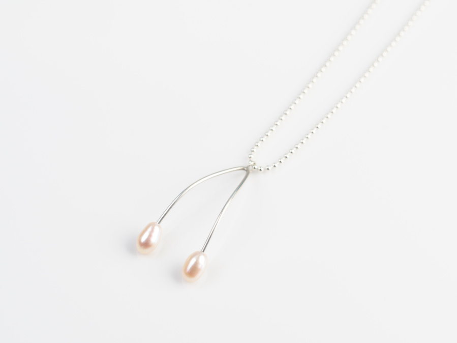 Sterling silver and white freshwater pearl pendant entitled Wish, against a white background. Made by contemporary jeweller Diane Allison, HALLISON Studios, Tasmania. This piece features 2 pearls and takes the shape of a wish bone. 