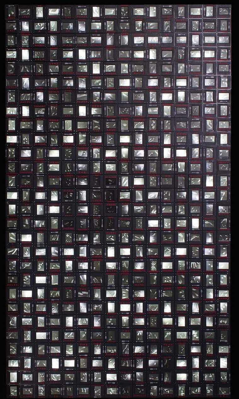 Press Upon Me by Tasmanian contemporary artist Patrick Hall of HALLISON Studios is an illuminated artwork made of 35mm slide mounts containing dozens of images of fingers and pins. Finalist in the Blake Art Prize, 2018.