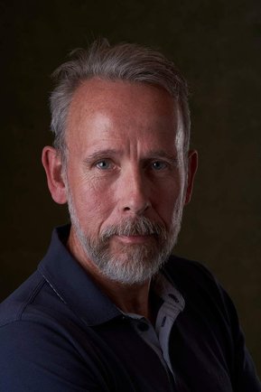 bearded man looking at the camera with a dark background. Headshot photographer - Clive Allcorn