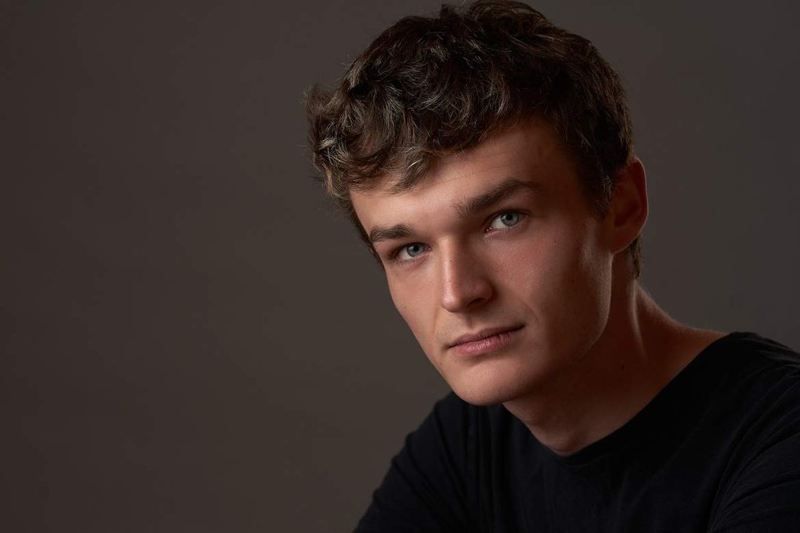 Portrait of young man with curly hair looking at the camera. Headshot Photographer - Clive Allcorn