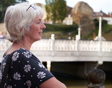 A woman with platinum hair to the left of the camera gazing into the distance with Tonbridge bridge in the background. Brand Photography by Clive Allcorn