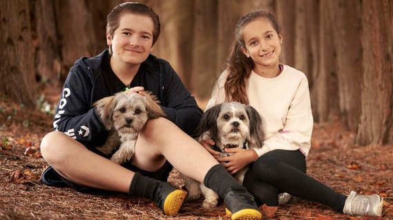 Portrait of two children seated on the ground in woodland with their two dogs. Portrait Photographer - Clive Allcorn