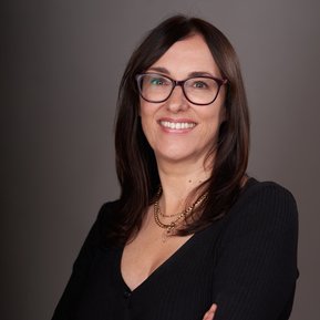 Half-length portrait of a smiling woman with long brown hair wearing glasses. 
Headshot Photography service by Clive Allcorn