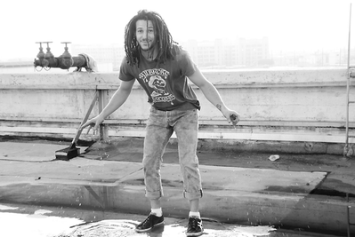 Portrait of a young white man with dreadlocks in a puddle 