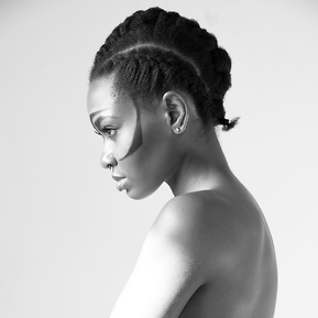 Black and white portrait of a young black topless woman with tribal hair and makeup