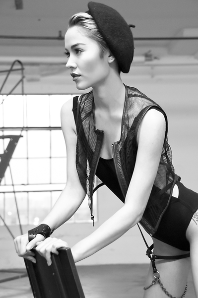 Black and white portrait of young white woman wearing all black, a leather garter and beret
