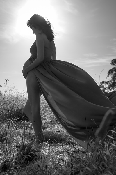 Black and white silhouette of a pregnant woman in a flowy dress
