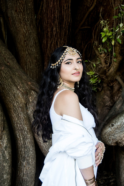 Pakistani young woman in white wearing traditional jewelry in a garden