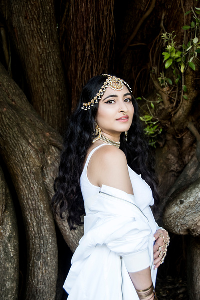 Pakistani young woman in white wearing traditional jewelry in a garden