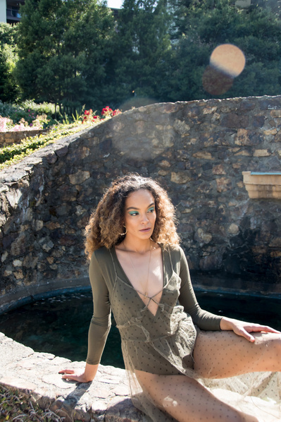 Portrait of a black woman wearing a green leotard and sheer fabric in a garden