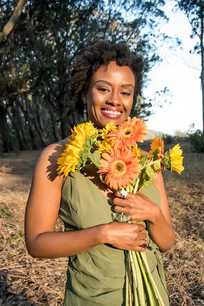Portrait of a black woman holding an assortment of flowers outdoors