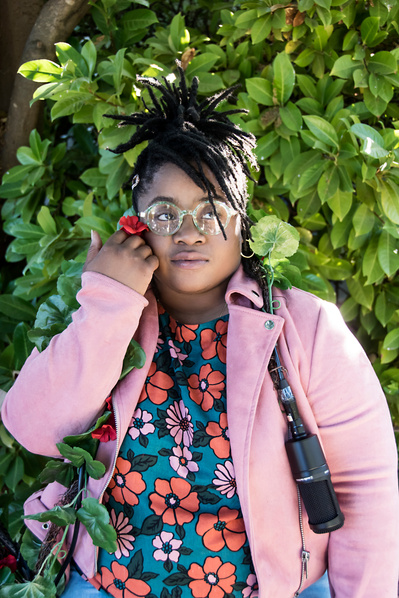 Portrait of a young black woman holding a microphone outdoors