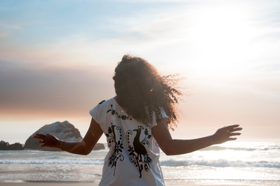 Curly haired woman at the beach at sunset