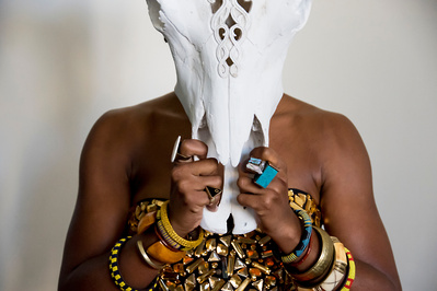 Portrait of a black woman wearing stacks of colorful ethnic rings and bracelets behind a bull skull