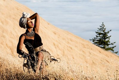 Black young woman wearing a head wrap on the side of a hill on a sunny day