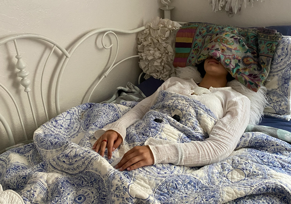 Young female past life regression client laying in bed in hypnosis during an in-home session