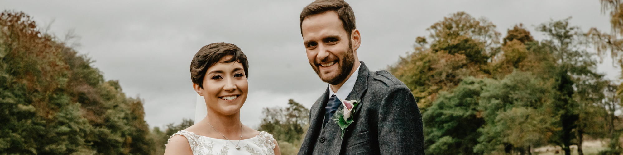 bride and groom standing in front of lake outdoors