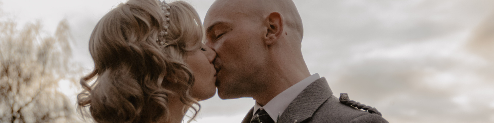 blonde bride and groom kissing in front of sunset on wedding day.