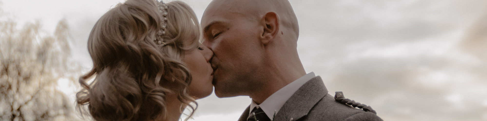 blonde bride and groom kissing in front of sunset on wedding day.